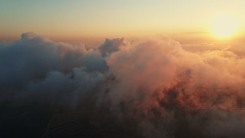 Moving white clouds blue sky scenic aerial view sunset summer. Drone flies high back in blue sky through fluffy clouds in evening golden sun summer. Sun is hidden behind clouds at fog. Relax. Nature