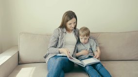 Mom prepares child for school and reads book with her son while sitting at home.