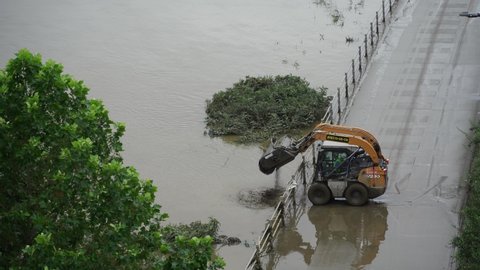Seoul, Korea - August  8,2020: Skid loader is cleaning up the mud and water piled up on the bike path next to the Han River due to torrential rain.