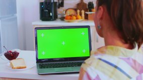 Working on tablet pc with green screen in kitchen during breakfast. Green screen chroma mock up isolated mockup background ready to be replaced with your text, logo or advertisement. Using internet - Powered by Shutterstock - Get 15% off with code: PIKWIZARD15