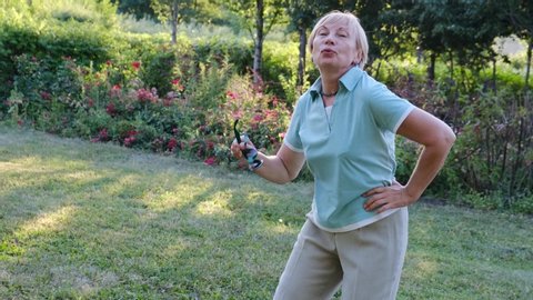 Elderly cheerful woman dancing outdoors in the park