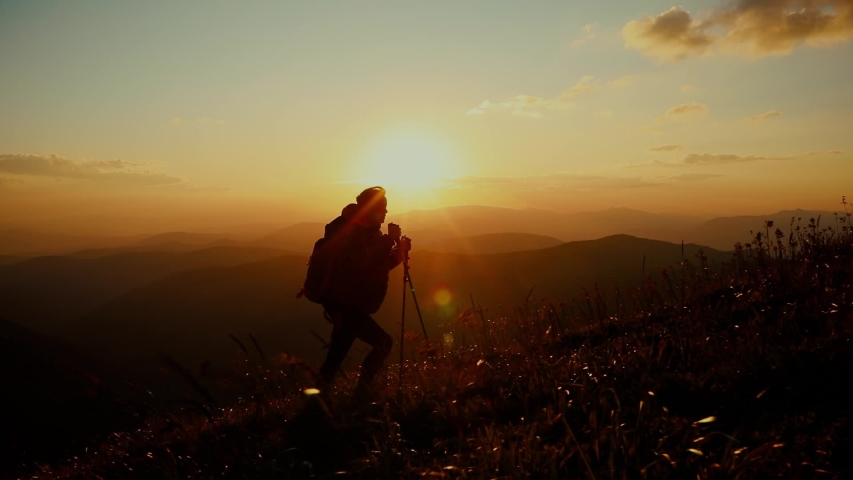 Epic shot of a woman hiking on the edge of the mountain in beautiful sunset. Camera follows hipster millennial young woman running up on top of mountain summit at sunset Royalty-Free Stock Footage #1057147976