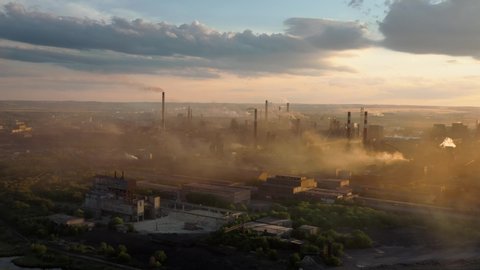 Drone shot of industrial zone with thick smog and burning fossil fuels. Zoom in aerial shot of factory zone shot from top, air pollution and soot in many factory chimneys in city area