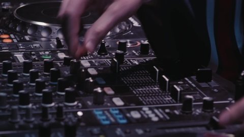 Close Up of Dj Mixer Controller Desk in Night Club Disco Party. DJ Hands touching Buttons and Sliders Playing Electronic Music