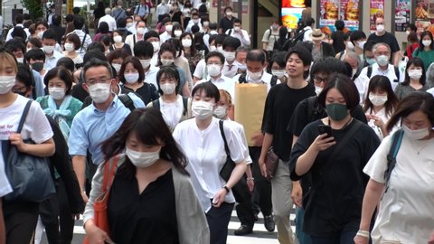 TOKYO, JAPAN - AUG 2020 : Crowd of people at the street near Shinjuku station in rush hour. Commuters wearing surgical mask to protect from Coronavirus (COVID-19) in hot summer season. Slow motion.