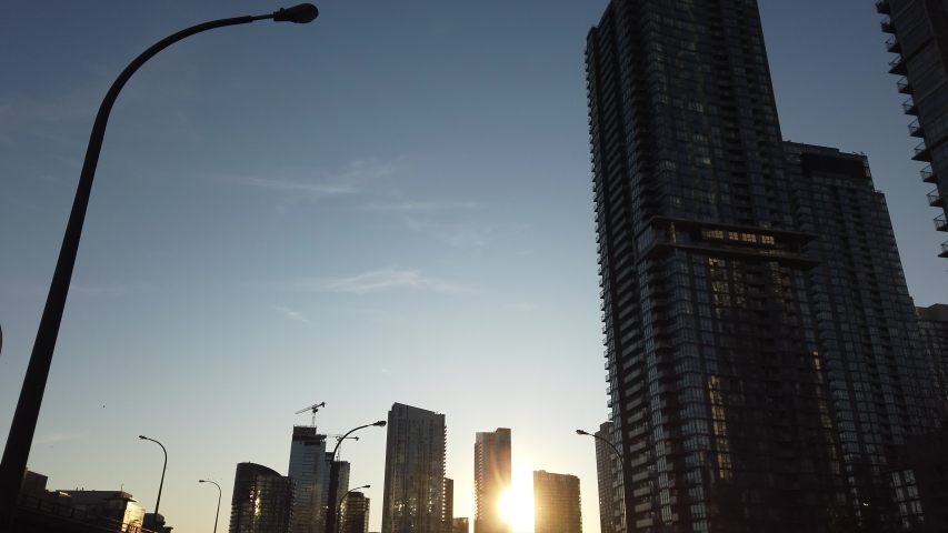 Wide moving shot driving along the Gardiner Expressway in Toronto, showing sunset, buildings and sky