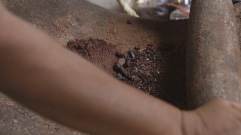 Grinding cacao beans using a rolling pin and stone surface to make chocolate in Oaxaca, Mexico. Extreme close up, slow motion.