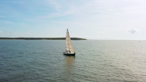 Fast aerial panning a sailboat with sails up from the front