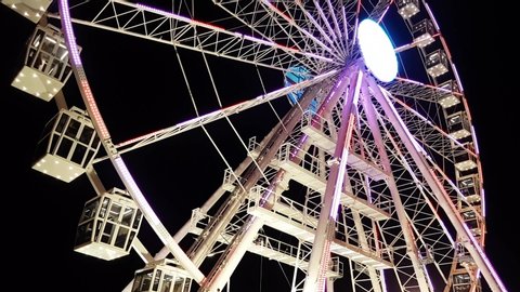 Ferris wheel. A ferris wheel rotates against the background of the night sky. Close-up of a Ferris wheel with night illumination. lluminated Ferris Wheel construction - Via Roma cagliari Ruota panoram