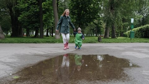 Family in a rainy park. Kids in a puddle. Child having fun outdoors.