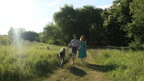 Lovely young couple walking in the park with their irish woulfhound dog, having fun together.