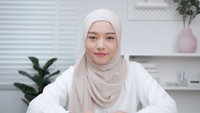 POV of Beautiful Young Muslim woman making a video call waving hand and enjoying communication talking with friend, family sit in home office
People Lifestyle and Online Communication Concept.