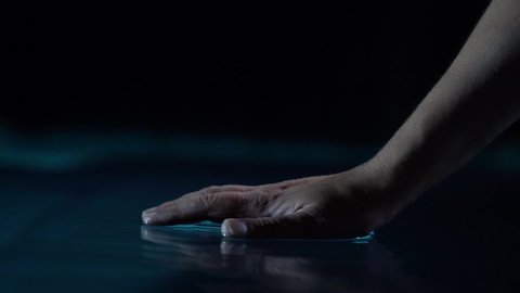 A close-up of a man hand touching the dark surface of the water, dripping from it. Beautiful lighting
