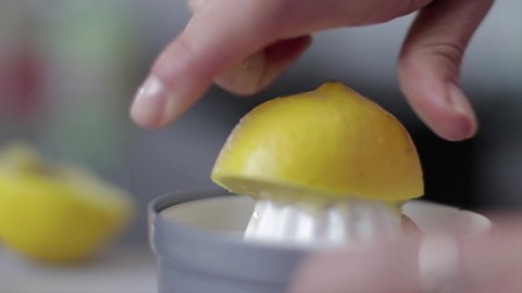 Persons fingers squeezing the lemon juice out of the lemon.