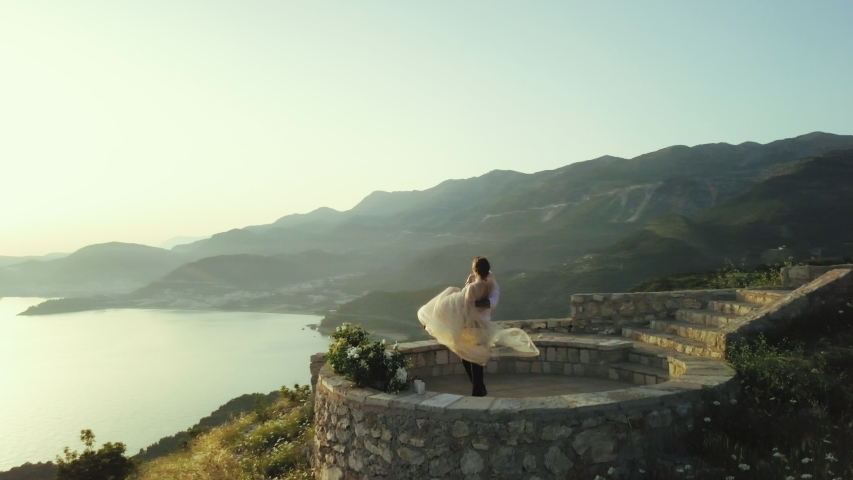Happy wedding couple spinning together at sunset on a mountain peak in Montenegro against nature sea landscape in Montenegro
 | Shutterstock HD Video #1057191076