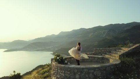 Happy wedding couple spinning together at sunset on a mountain peak in Montenegro against nature sea landscape in Montenegro

