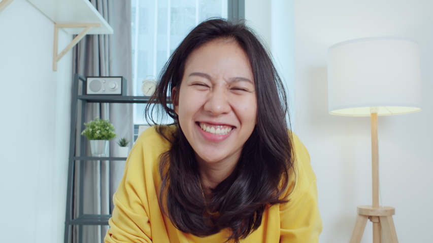 Young Asian woman look at camera, greeting and talk to friends or family on video call online meeting at home. Remote internet conference, social distancing, new normal lifestyle 2020 concept Royalty-Free Stock Footage #1057194193