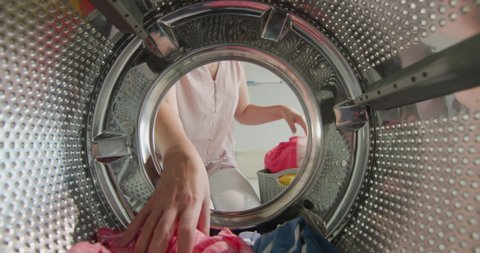 Housewife pulls multicolored laundry from washing machine