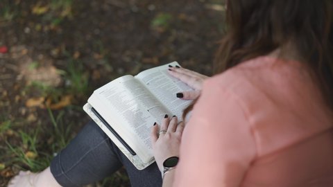 Silhouette of a Woman reading a bible alone in a park during the day
