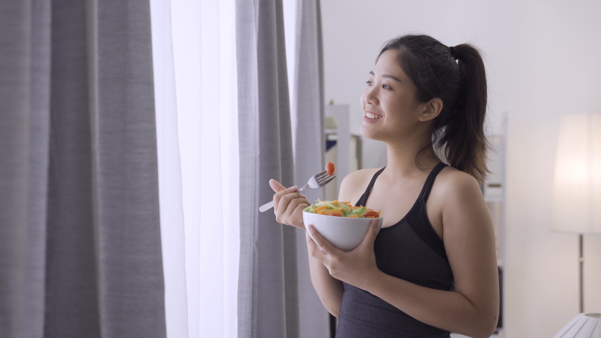 elegant asian chinese woman eating healthy salad after working out at home. Royalty-Free Stock Footage #1057203763