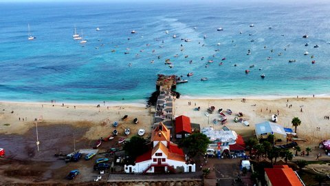 Aerial shot of the wooden pier of Santa Maria on the island of Sal, Cape Verde. Camera approaches the wide sandy beach towards the pier.