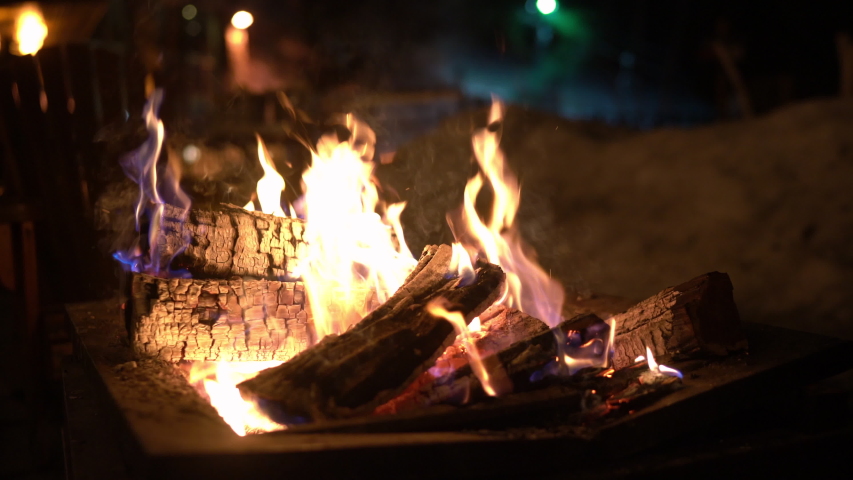Campfire in firepit oudoors in winter with snow. Burning fire with firewood.