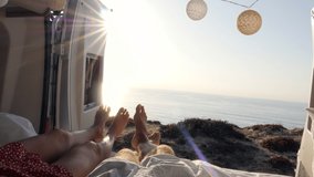 Point of view of couple's feet hanging out from van. Van lifestyle couple on camper van bed enjoys stunning ocean view  - Powered by Shutterstock - Get 15% off with code: PIKWIZARD15
