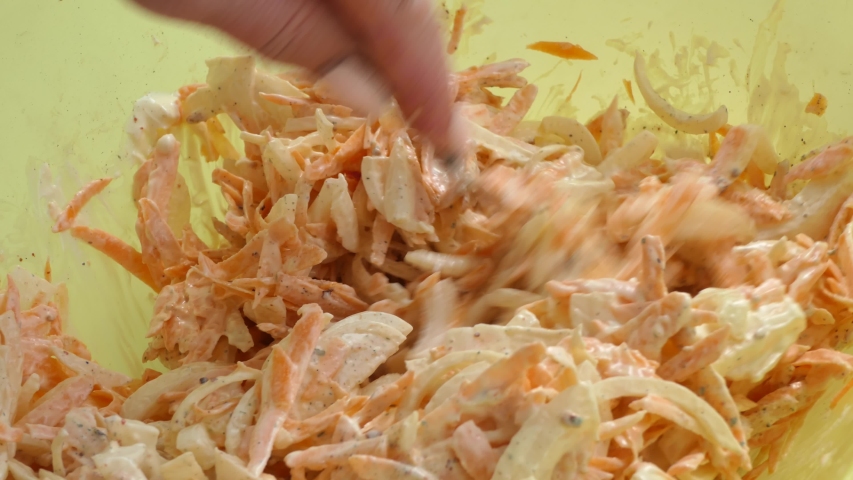 Simple food, a dish of Asian cuisine. The cook mixes chopped onions, carrots and mayonnaise with a spoon. Close up.