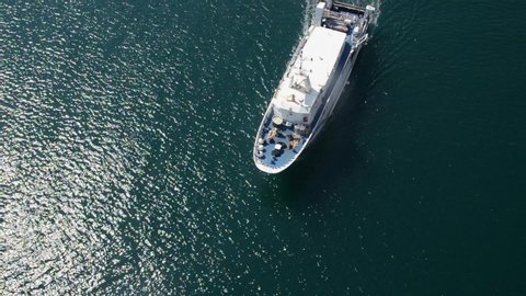 Aerial view of white boat on a deep blue sea. Ship at sea leaving a wake. Summer seascape. Travel with boat at ocean. Luxurious yacht with tourists on a sea. Holidays