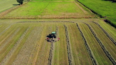 tractor collects hay on the field. Rural work on the preparation of feed for livestock. Packed bales of hay. Life outside the city. Quadrocopter video filming from the air. Milan Italy. summer