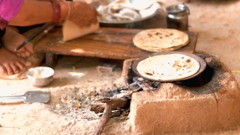 Female making Indian Bread ( rotis )on stove in Gujarat India, traditional indian food roti or Chapati,Traditional way of making indian Roti or chapati in indian outdoor,
