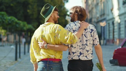 Shot back young gay couple hold hands hug each other walk at street friendship relationship lifestyle concept homosexual dating intersection travel outdoors lgbt slow motion