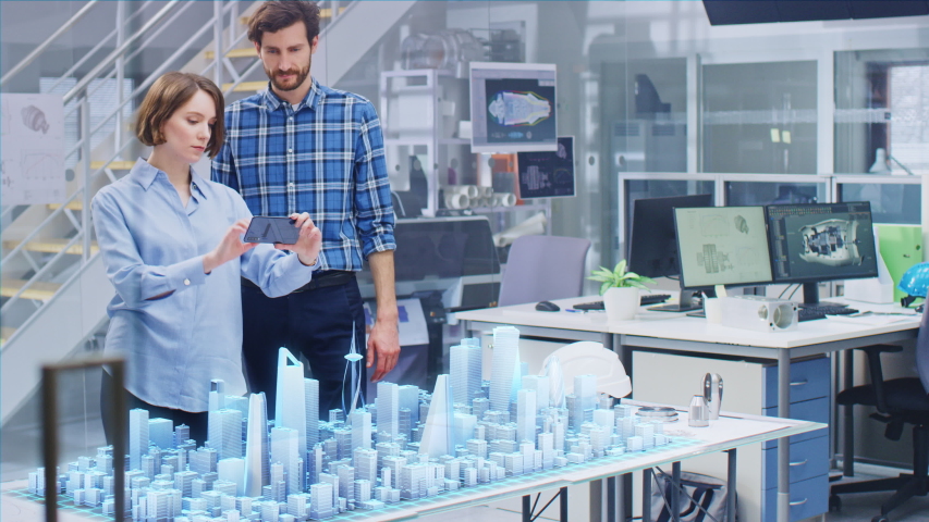 Architect and Engineer have Discussion, Use Augmented Reality Smartphone to Design Sustainable 3D Megalopolis City Model. Futuristic Office with Architectural Designers. Graphical Animation VFX  Royalty-Free Stock Footage #1057229611