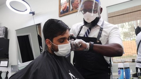 Washington, DC / USA - May 31, 2020: A man at a barbershop has his hair cut while wearing a face mask during the COVID-19 pandemic. 