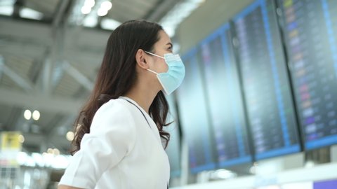 A traveller woman is wearing protective mask in International airport, travel under Covid-19 pandemic, safety travels, social distancing protocol, New normal travel concept .
