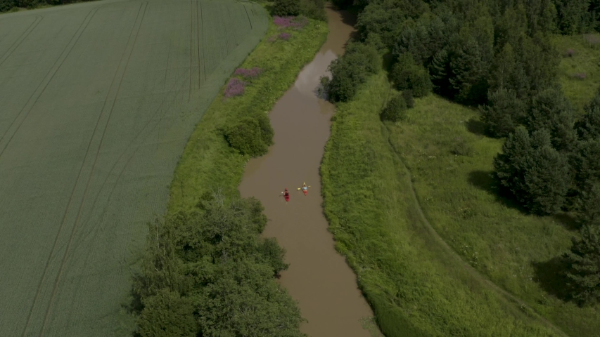 Beautiful aerial pan up of two people in colorful kayaks along the Keravanjoki River in Kerava, Finland.