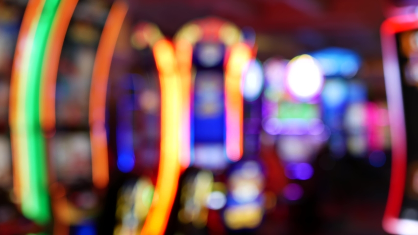 Defocused slot machines glow in casino on fabulous Las Vegas Strip, USA. Blurred gambling jackpot slots in hotel near Fremont street. Illuminated neon fruit machine for risk money playing and betting. Royalty-Free Stock Footage #1057248238
