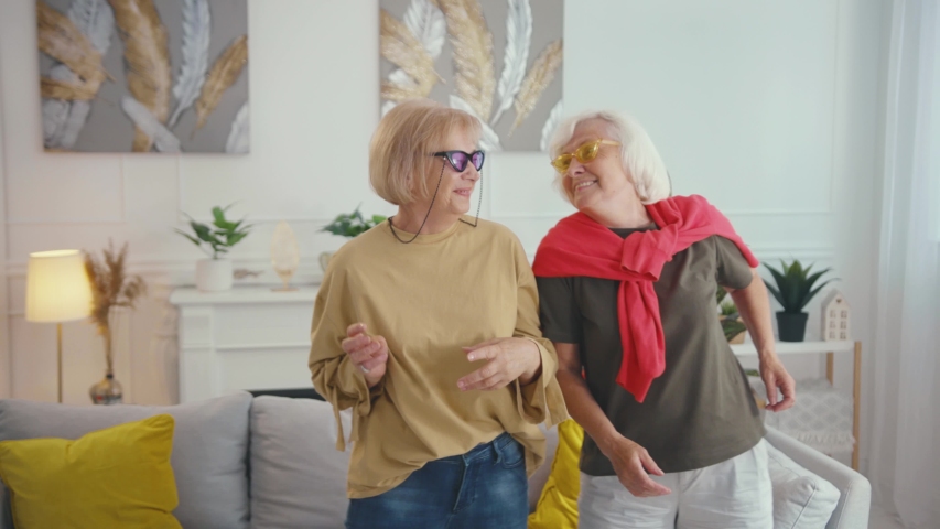 Couple of happy beautiful old fashion grandmas dancing out together in stylish apartment living room. Friendship. Two grandmothers having party. Slow motion. Royalty-Free Stock Footage #1057250995