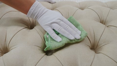 Hotel and apartment cleaning. Soft furniture surface being cleaned by pretty maid with wipe in hands. woman removing dirty stains from upholstered furniture with wipe dipped in detergent. 4k