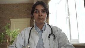 Indian doctor talking to camera making online video call consulting patient. Female gp looking at webcamera speaking in conference chat. Webcam face view. Telemedicine in India, telehealth consultancy