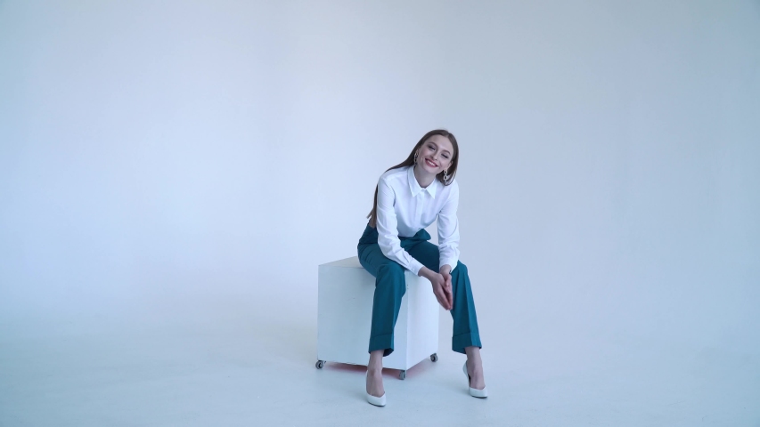 A business lady is sitting in a business suit on a chair on a white background.