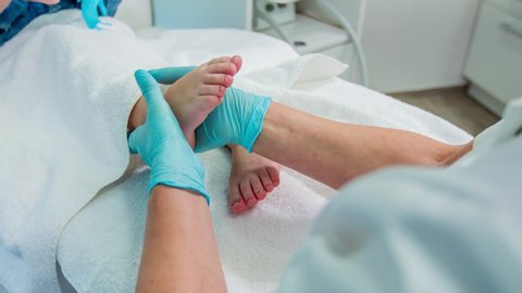 Professional reflexologist gently rubs cream into baby foot by massage
