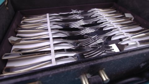 set of elegant cutlery in vintage leather case on light blue