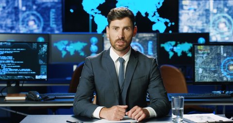 Caucasian handsome man in suit and tie sitting at table and talking to camera like news reporter. Male spokesman telling about digital security on TV. Government representative having speech.