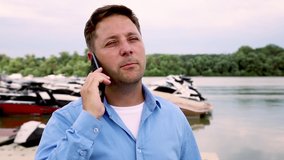 Man talking on the phone at port with Yachts and boats in background. Nautical and marine concept. Slow motion video in 60 fps
