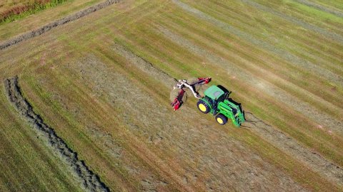 tractor collects hay on the field. Rural work on the preparation of feed for livestock. Packed bales of hay. Life outside the city. Quadrocopter video filming from the air. Milan Italy 10.09.2020