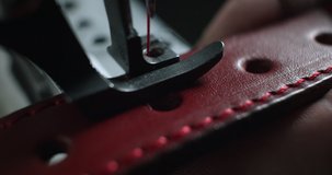 Close-up view of tailor works on sewing machine in private leather craftshop, stitching belt in process. male seamstress sewing leather belt in leather workshop in 4k slow motion