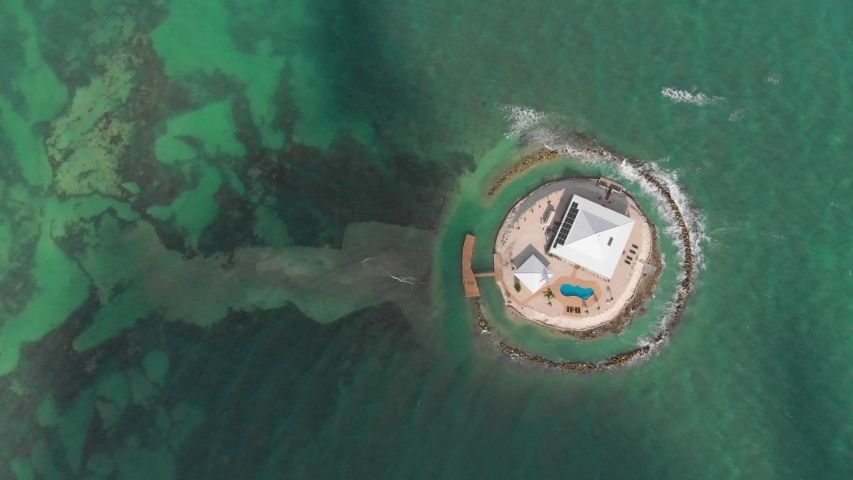 Aerial view of the private lonely villa in the middle of the ocean. Solar panels green energy Florida Key West Key beach during summer season blue sky green water clear nature swim pool