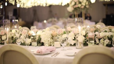 Wedding table rustic style decor with dishes, drinks and flowers in pink and beige colours. Floristic compositions of roses on party banquet dining table.
