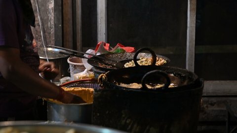 Mirchi Bada is being fried in oil on a frying pan by a street food seller in roadside in the evening. Shot at Jodhpur, Rajasthan, India.